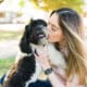 Woman Kissing Her Shih Tzu Dog After Playing In The Park